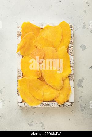 Slices of large sweet dried mangoes in wooden box.Top view. Stock Photo