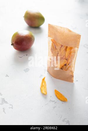 Pack of dried mango slices with two fresh raw mangoes. Top view. Stock Photo