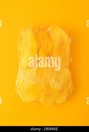 Large dried sweet mango slices on yellow background. Stock Photo