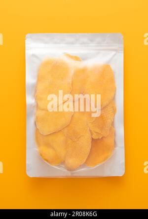 Jumbo pack of dried large sweet mango slices on yellow background.Top view. Stock Photo