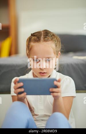 Serious concentrated girl playing game on smartphone Stock Photo