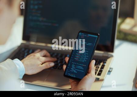 Closeup on modern female with laptop and smartphone working on cyber security firewall protection in modern office. Stock Photo