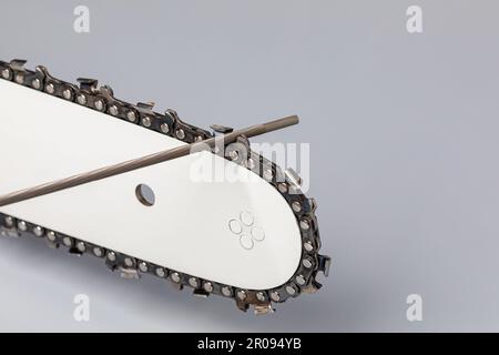 Sharpening chainsaw chain with file. Chain saw and lawn equipment maintenance, repair and service concept. Stock Photo