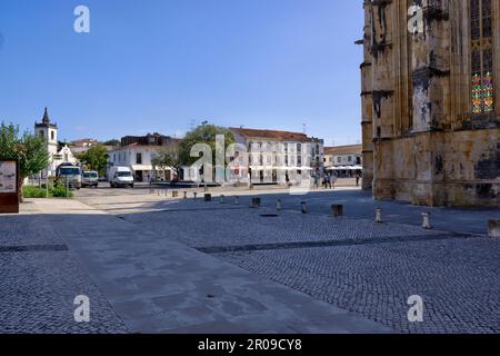 Batalha, Portugal - August 15, 2022: Town square with restaurants, shops and numerous tourists some motion blurred with part of the Monastery in frame Stock Photo