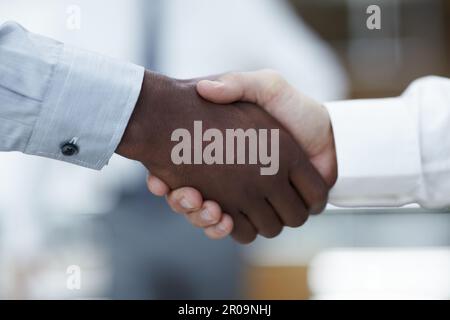 Business partners - Sealing the deal. Close up of a handshake between an African businessman and a Caucasian businessman. Stock Photo