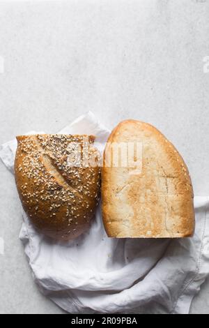 Loaf of artisan bread topped with sesame seeds cut into half, top view of sesame coated bread, sandwich bread cut into half Stock Photo