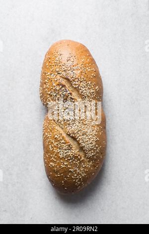 Loaf of artisan bread topped with sesame seeds on a marble countertop, top view of sesame coated bread, sandwich bread on a white tray Stock Photo