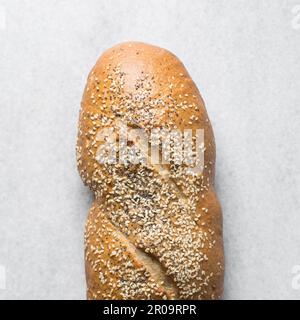 Loaf of artisan bread topped with sesame seeds on a marble countertop, top view of sesame coated bread, sandwich bread on a white tray Stock Photo