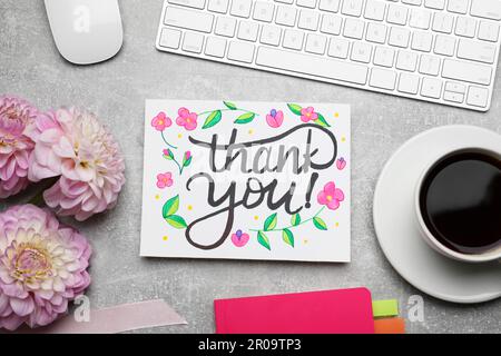 Card with phrase Thank You, dahlias, coffee and notebook on grey table, flat lay Stock Photo