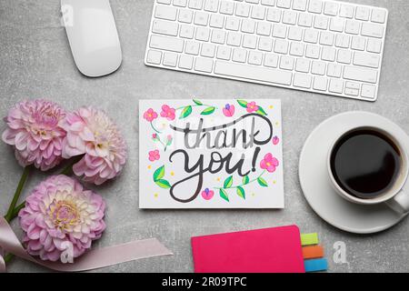 Card with phrase Thank You, dahlias, coffee and notebook on grey table, flat lay Stock Photo