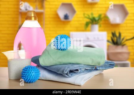 Dryer balls, detergents and stacked clean clothes on wooden table in laundry room Stock Photo