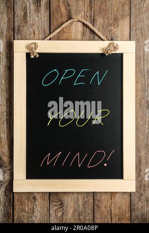 Small chalkboard with motivational quote Open your mind hanging on wooden wall Stock Photo