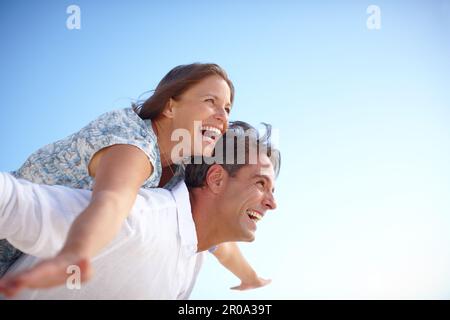 Feeling the freedom of the great outdoors. A mature man with his happy wife on his back both with their arms outstretched. Stock Photo