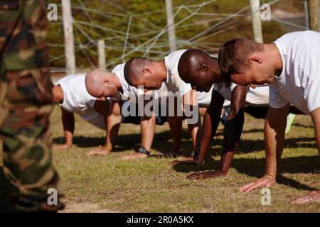 Feeling the burn...a group of men doing push-ups at a military bootcamp. Stock Photo