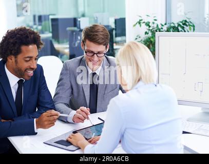 Focusing on the latest information. three colleagues in an office looking at a digital tablet. Stock Photo