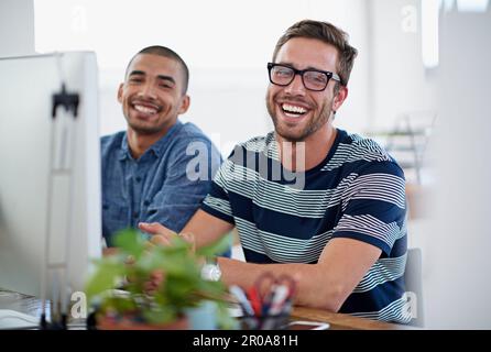 Another project done to perfection. Portrait of two smiling coworkers sitting at a computer in an office. Stock Photo