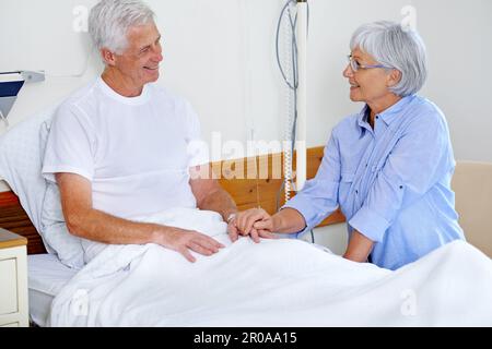 For better or worse. a sick man in a hospital bed being comforted by his wife. Stock Photo