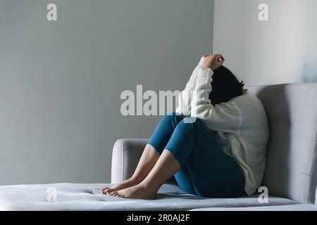 Concept of sad teenage girl depression. Upset teenage girl sitting at window indoors. Anxiety young woman Despair and stress. Lonely and unhappy femal Stock Photo