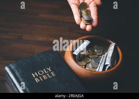 One tenth or tithe is basis on which Bible teaches us to give one tenth of first fruit to God. coins with Holy Bible. Biblical concept of Christian of Stock Photo