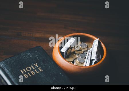 One tenth or tithe is basis on which Bible teaches us to give one tenth of first fruit to God. coins with Holy Bible. Biblical concept of Christian of Stock Photo