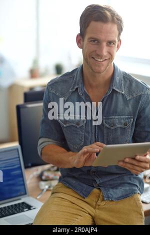 Doing some project planning online. A young man reading his text messages while standing in his office. Stock Photo