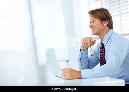 Dreaming of bigger business opportunities. Profile shot of a smiling mature businessman working at his laptop. Stock Photo