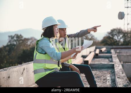 Two specialists inspect commercial, Industrial building construction site. Real estate project with civil engineer, designing commercial buildings on Stock Photo