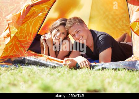 They a camping couple. Portrait of a happy young couple lying in a tent. Stock Photo