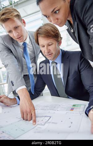 Sharing ideas and opinions. A group of architects reviewing building plans in their office. Stock Photo