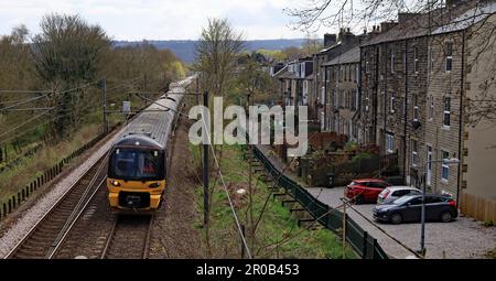 A northern train service from Bradford Foster Sq to Skipton passes to the west of Keighley through the village of Utley alongside Royd Street. Stock Photo