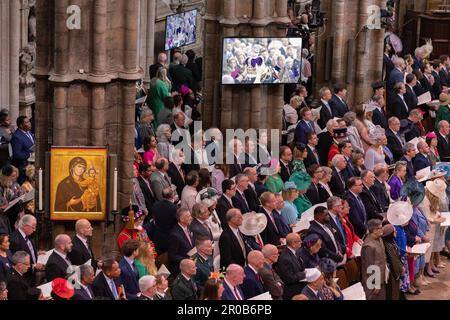 Guests and members of the congregation watch the Coronation rituals on screens inside the Westminster Abbey of The King Charles III and Queen Consort. Stock Photo