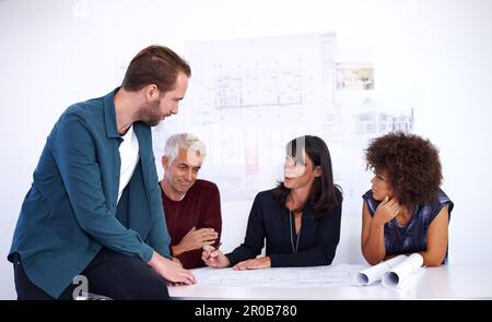 Going over the nuts and bolts of their design. a group of architects working together on building plans. Stock Photo
