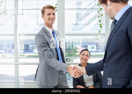 Hes just been promoted. two businessmen shaking hands in an office setting. Stock Photo