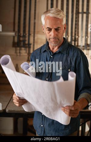 Hope for the best but make sure you plan for the worst. a senior man assessing his building plans. Stock Photo