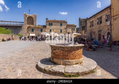 Monteriggioni, Siena Province, Tuscany, Italy.  The cistern in Piazza Roma and in the background the tower over the main gate of the walled town. Stock Photo