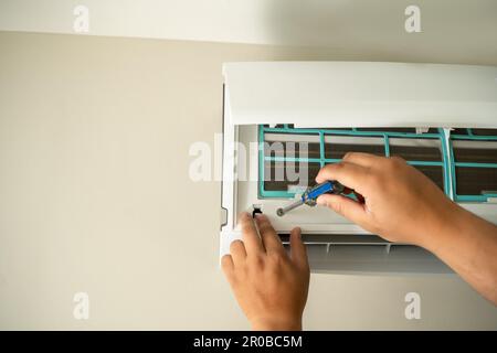 Male professional technician fixing An electrician repairs an air conditioner indoors. removing air filter repairing hot temperatures Stock Photo