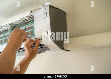 Male professional technician fixing An electrician repairs an air conditioner indoors. removing air filter repairing hot temperatures Stock Photo
