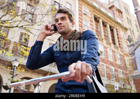 On the move. a man talking on his cellphone while riding a bicycle in the city. Stock Photo