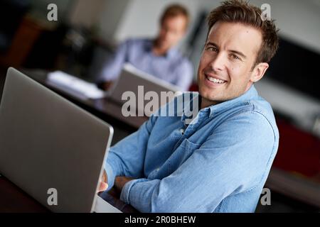 This workspace is my happy place. a man working on a laptop in an office. Stock Photo