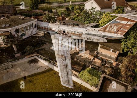 An eerie view of abandoned airplanes scattered near a control tower in a deserted aviation site. Stock Photo