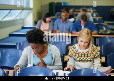 Working hard for a good future. two female college students working together in a lecture hall. Stock Photo