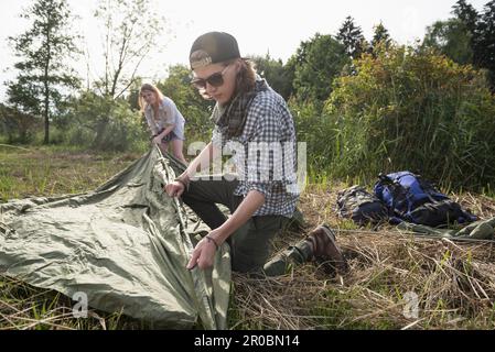 Young couple setting up tent in a forest, Bavaria, Germany Stock Photo