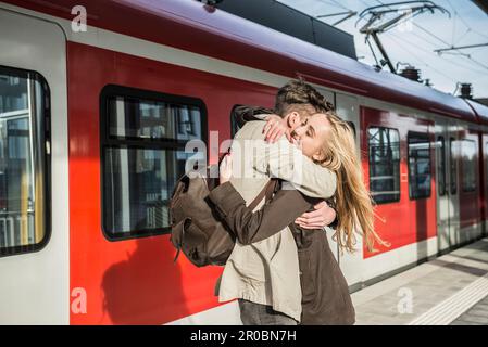 Young couple hugging at train station, Munich, Bavaria, Germany Stock Photo