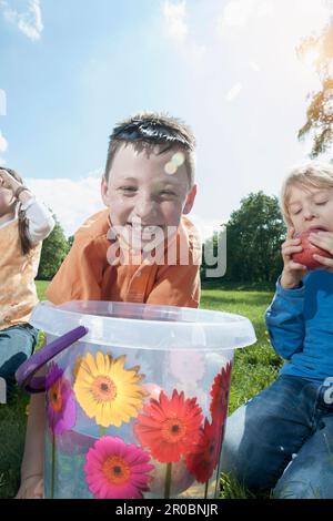 Boy trying to take apple out of a bucket with their mouth, Munich, Bavaria, Germany Stock Photo