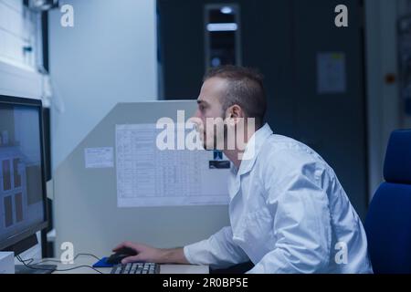Young male scientist working on computer in an optical laboratory, Freiburg im Breisgau, Baden-WÃ¼rttemberg, Germany Stock Photo