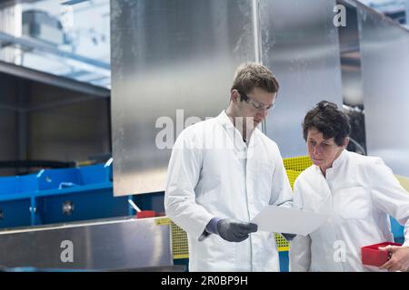Two engineers looking at report in an industrial plant, Freiburg Im Breisgau, Baden-WÃ¼rttemberg, Germany Stock Photo