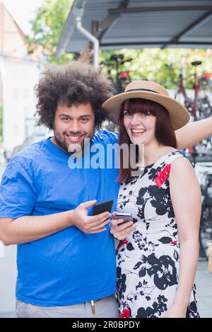 Portrait of happy couple using mobile phones in city Stock Photo