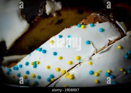 Sliced Easter cake close-up. Sweet white icing and colored decorative powder Stock Photo