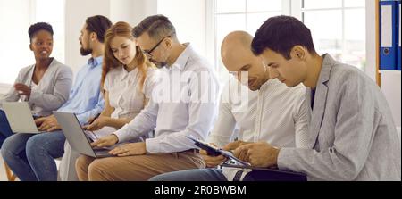 Team of diverse business people sitting in office, discussing work and using laptops Stock Photo