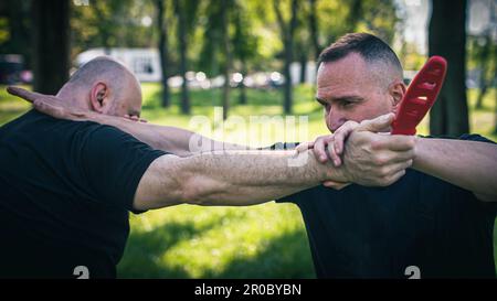 Knife attack self-defense. Techniques of disarming knife attacker. Weapon disarm training Stock Photo